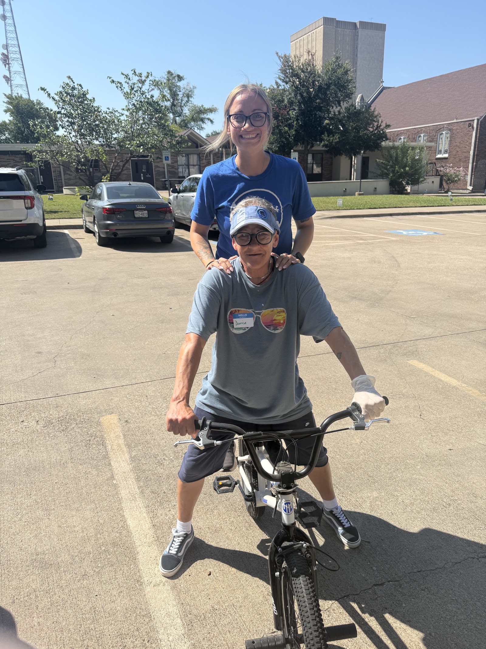 Donica smiling on her bicycle with a Metro Relief friend behind her