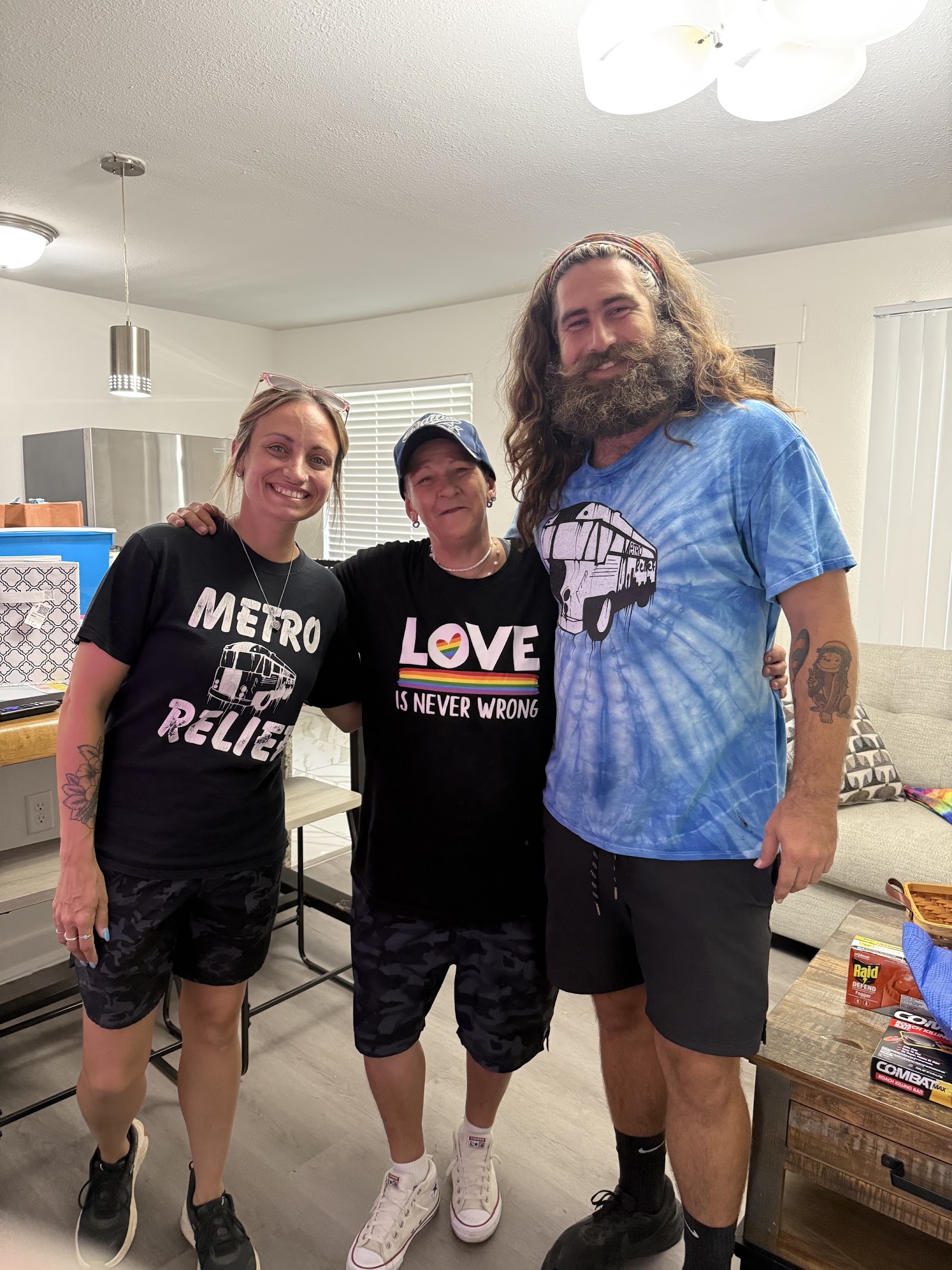 Donica smiling at home with two members of her community